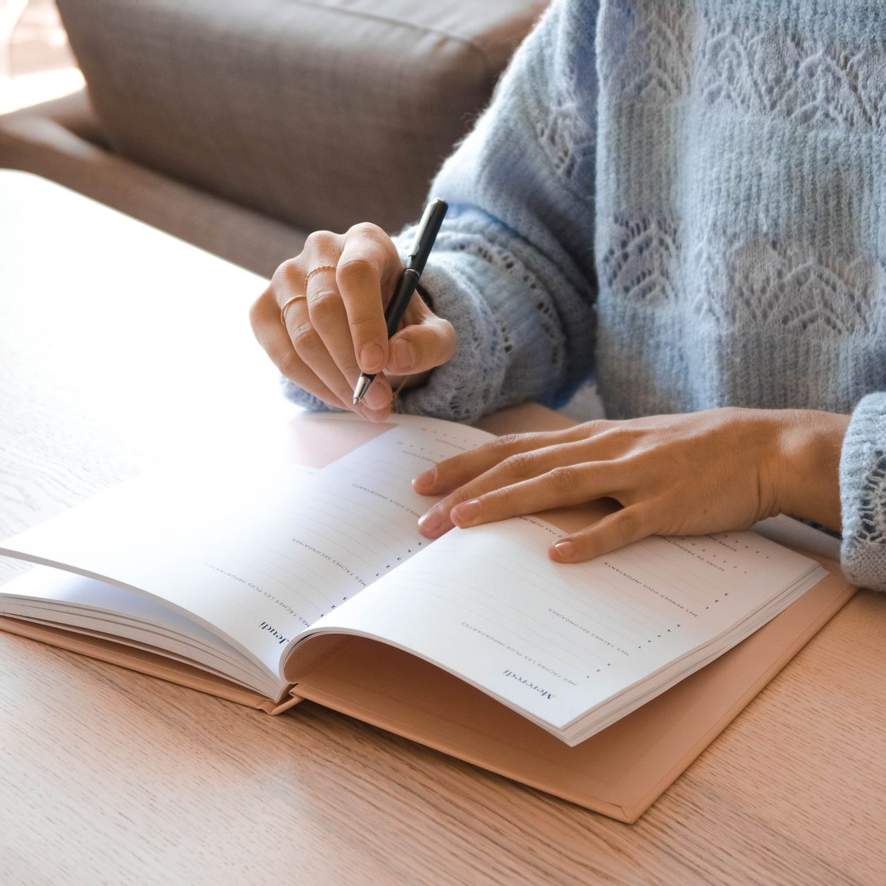 woman in white and gray sweater writing on white paper
